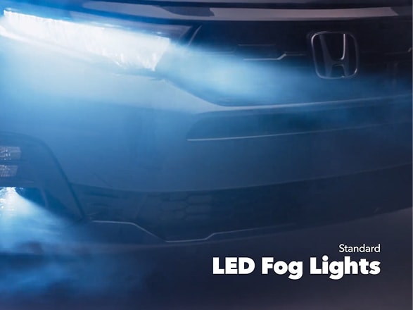 Frente de la Honda Odyssey Elite 2027 en Smoke Blue Pearl en un estudio mostrando las luces delanteras y los faros antiniebla de LED estándar (minivan).